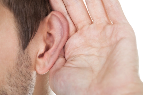 Man holding hand up to ear