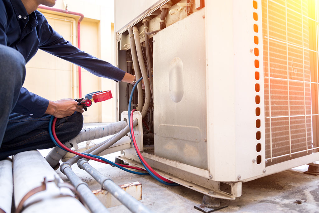 HVAC technician working on controls of air conditioner